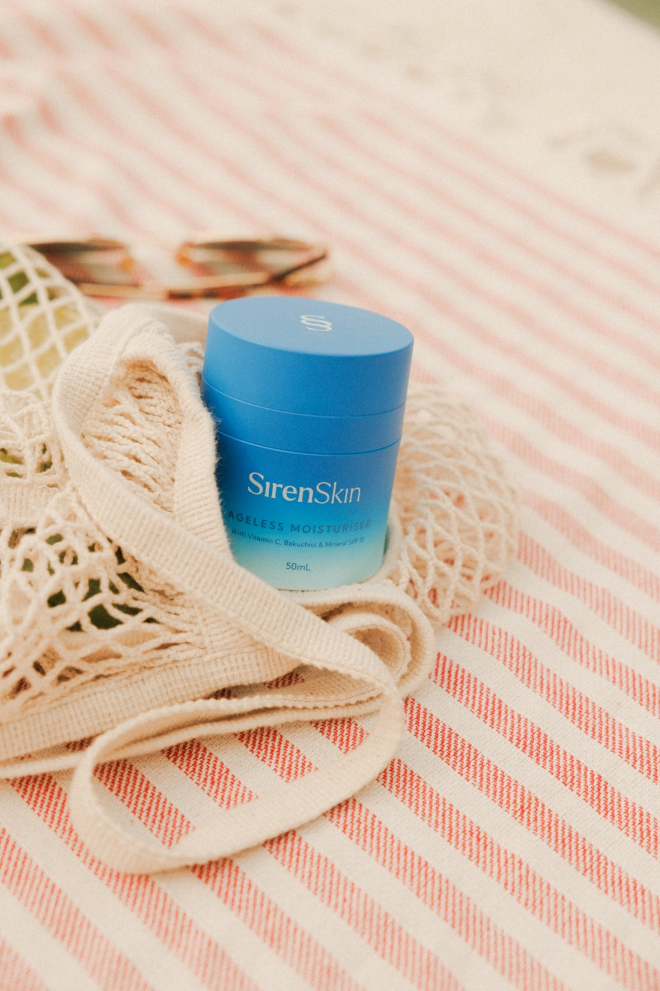 Blue pregnancy & breastfeeding-safe skincare jar on a striped fabric background